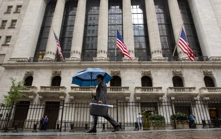 © Reuters. Man carries an umbrella in the rain as he passes the New York Stock Exchange