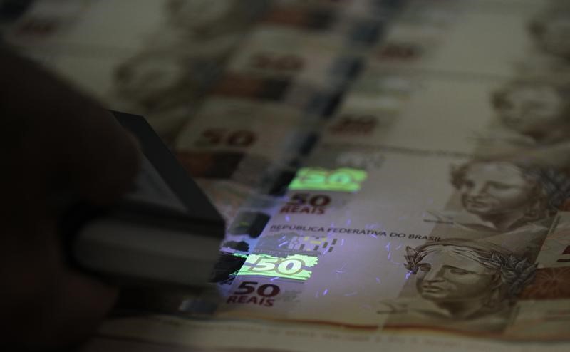 © Reuters. Funcionário verifica folhas de papel-moeda durante visita à Casa da Moeda