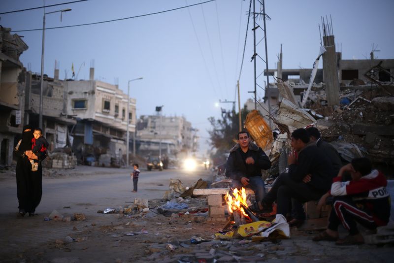 © Reuters. Palestinos se esquentam em uma fogueira perto dos escombros de casas que dizem terem sido destruídas em bombardeios de Israel, durante o mais recente conflito entre israelense e mlitantes do Hamas, em Gaza 