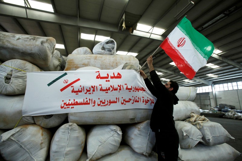 © Reuters. A man places an Iranian flag on bags of Iranian humanitarian aid at the port of Beirut