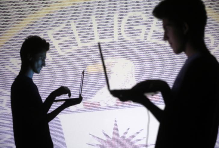 © Reuters. People pose with laptops in front of projection of  binary code and CIA emblem in this picture illustration taken in Zenica