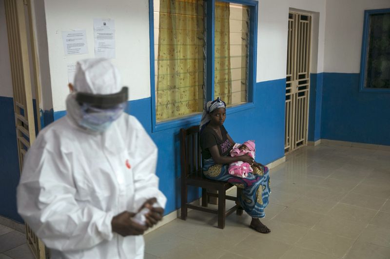 © Reuters. Health worker walks past a woman holding a baby at the maternity ward in the government hospital in Koidu, Kono district in eastern Sierra Leone