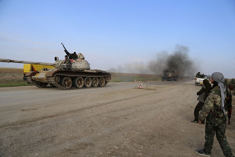 © Reuters. A military tank is driven past YPG and PKK fighters manning a checkpoint on a highway connecting the Iraqi-Syrian border town of Rabia and the town of Snuny, north of Mount Sinjar