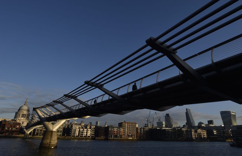 © Reuters. Workers cross the Millenium Bridge during the morning rush hour in the City of London