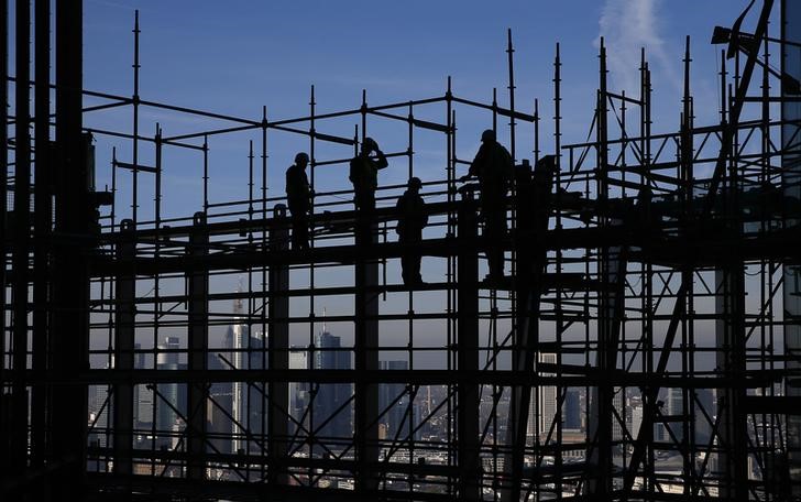 © Reuters. Construction workers are silhouetted while standing on a scaffolding at the construction site of the new headquarters of the European Central Bank (ECB) during a guided media tour in Frankfurt