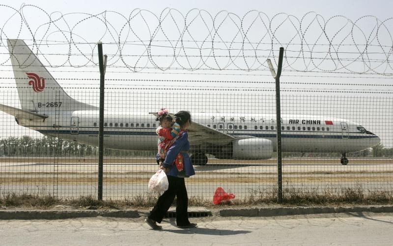 © Reuters. Chinese residents look at Air China Boeing aircraft taxiing on tarmac of Beijing's international airport