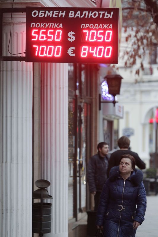 © Reuters. Женщина проходит мимо вывески пункта обмена валют в Москве