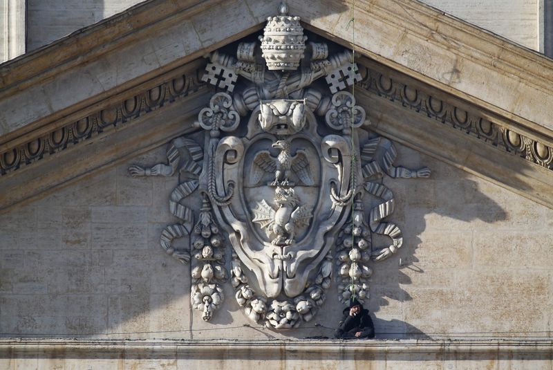 © Reuters. O italiano Marcello di Finizio sentado no alto da fachada da Basílica de São Pedro