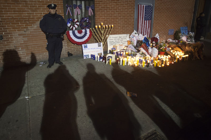 © Reuters. Police stand solemn vigil late at night at a makeshift memorial at the site where two police officers were shot in the head in the Brooklyn borough of New York