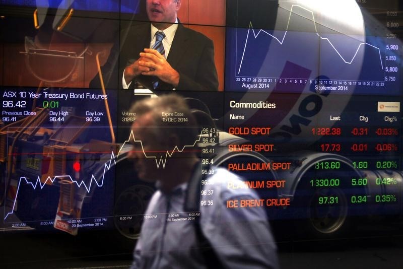 © Reuters. Pedestrian is reflected in the window of the Australian Securities Exchange with boards displaying stock movements in central Sydney