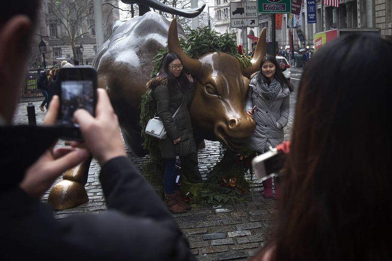© Reuters. TTourists pose for photos with the Wall Street bull statue in the Manhattan Borough of New York