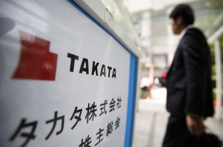 © Reuters. A man walks past a sign board of Japanese auto parts maker Takata Corp's Annual General Meeting in Tokyo