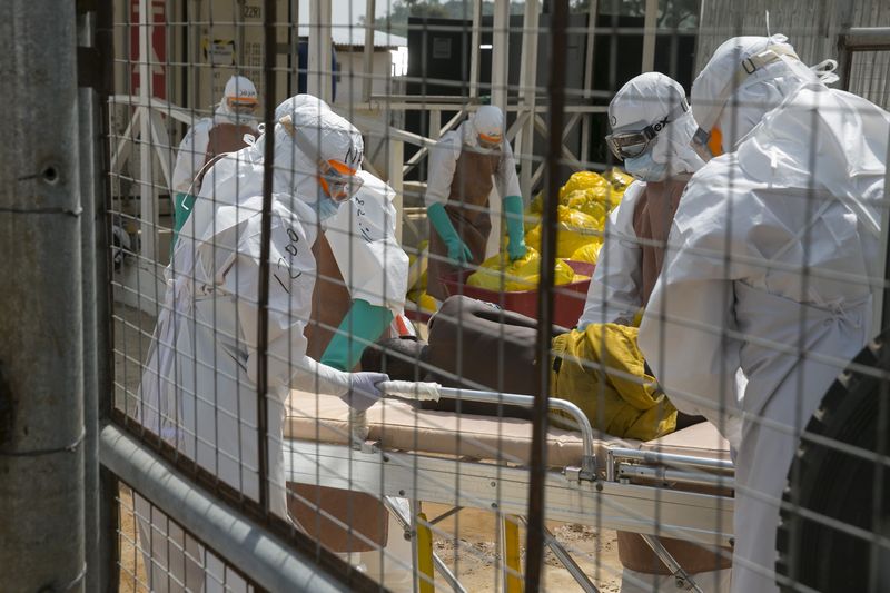 © Reuters. Profissionais britânicos transferem um recém-internado paciente com Ebola para maca, em Freetown