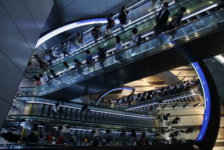 © Reuters. People ride on escalators at a shopping complex in Tokyo