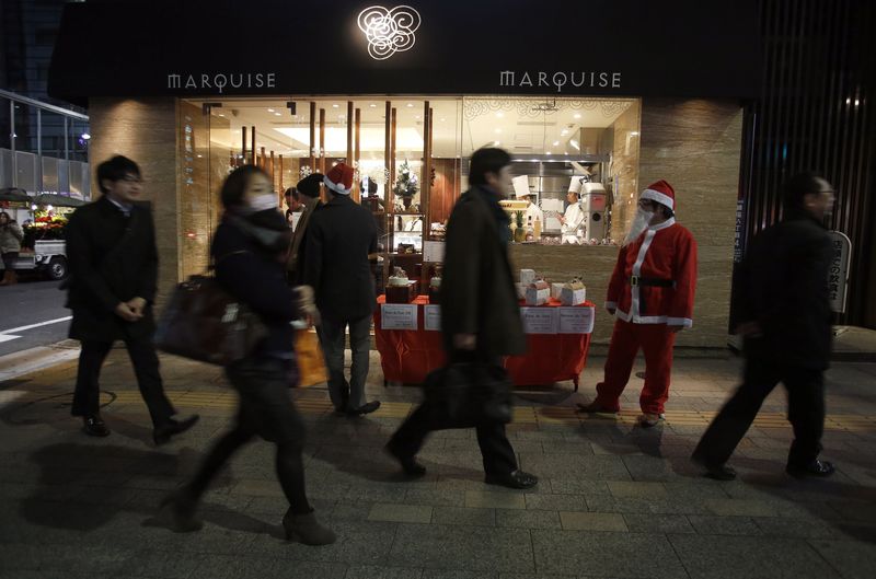 © Reuters. A man dressed as Santa Claus promotes Christmas cakes to pedestrians outside a pastry store in Tokyo