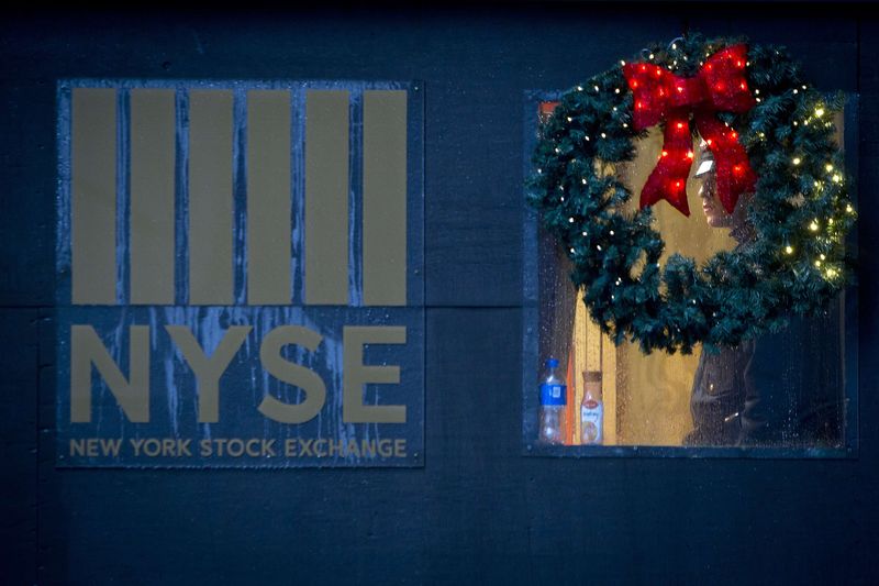 © Reuters. A police officer is pictured though a wreath as he stands guard in the rain at the New York Stock Exchange on the last day of trading before Christmas in the Manhattan borough of New York