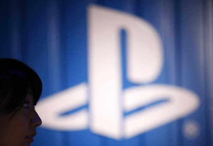 © Reuters. The logo of Sony Corp's PlayStation is seen next to a woman at its booth during the Tokyo Game Show 2014 in Makuhar
