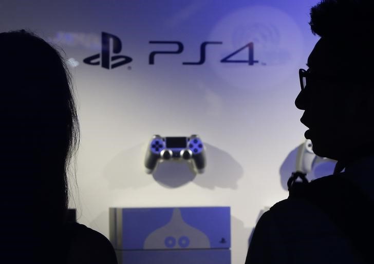© Reuters. Visitors looks at Sony Corp's PlayStation 4 game consoles and control pads displayed at a booth during the Tokyo Game Show 2014 in Makuhari