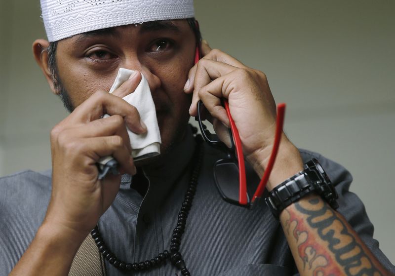 © Reuters. An Indonesian man, whose wife is a passenger onboard the missing AirAsia flight QZ8501, makes a phone call at a waiting area in Juanda International Airport, Surabaya