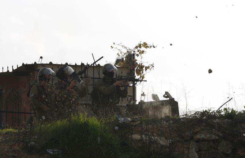 © Reuters. Israeli soldiers aim their weapons at Palestinian stone-throwers during clashes near Israel's Ofer Prison, near Ramallah