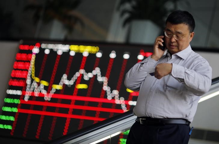 © Reuters. Un uomo al telefono nella sede dello Shanghai Stock Exchange