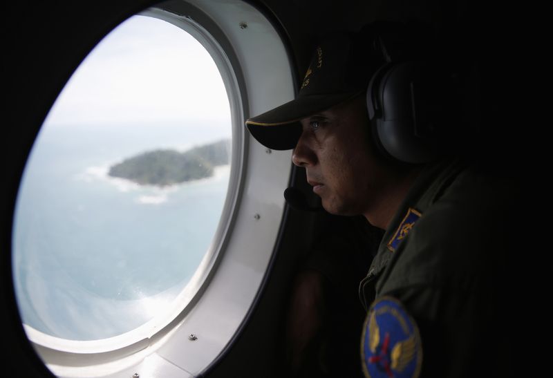 © Reuters. Membro da Marinha da Indonésia olha pela janela de uma aeronave de busca e resgate enquanto procuram por um voo da AirAsia desaparecido, ao norte da ilha de Bangka 