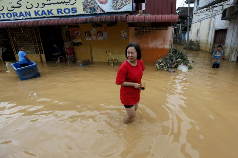 © Reuters. Mulher caminha na água em rua alagada de Kota Bharu, na Malásia 