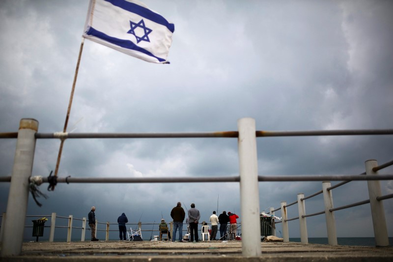 © Reuters. Fishermen cast their lines on the shore of the Mediterranean Sea in Ashdod