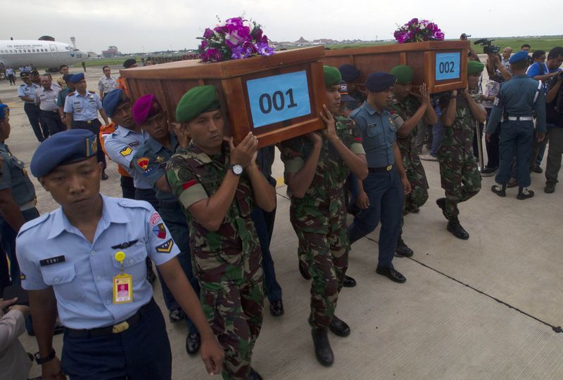 © Reuters. Militares da Indonésia carregam corpos de duas vítimas do avião da AirAsia