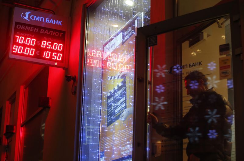 © Reuters. A man walks out of a building past a board showing currency exchange rates in Moscow