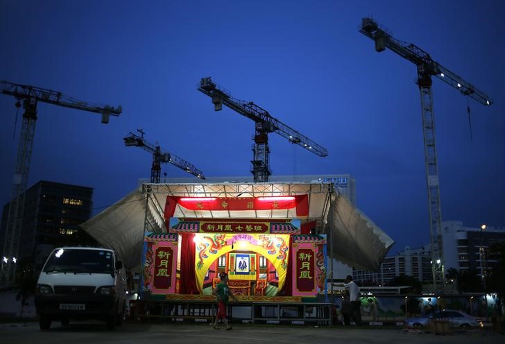 © Reuters. A performer walks past a traditional Chinese opera stage built next to the construction site in a public housing neighbourhood during the Hungry Ghost festival in Singapore