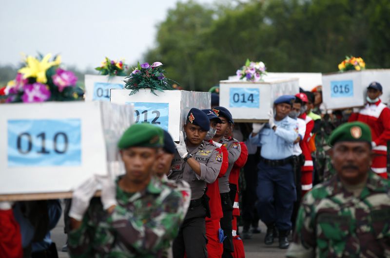 © Reuters. Caixões com corpos de vítimas de acidente da AirAsia, que serão transportadas em avião militar no aeroporto em Pangkalan Bun