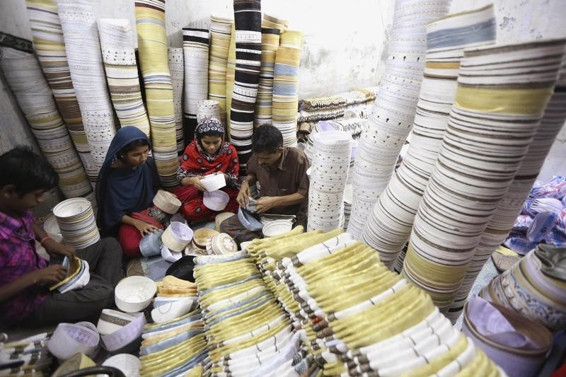 © Reuters. Workers sew prayer caps in a factory in old Dhaka