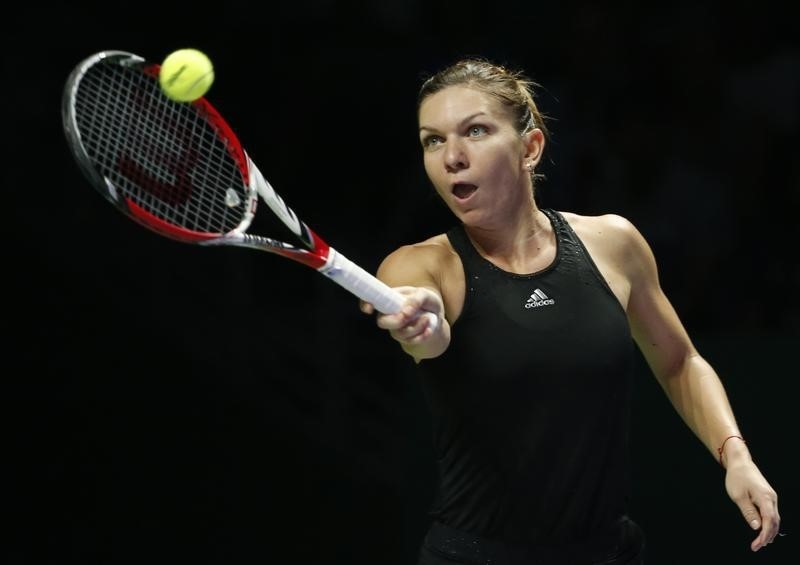 © Reuters. Simona Halep of Romania hits a return to Agnieszka Radwanska of Poland during their WTA Finals singles semi-final tennis match at the Singapore Indoor Stadium