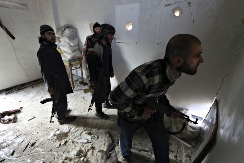 © Reuters. Rebel fighters stand in a room as one of them peeks out at the frontline against forces loyal to Syria's President Bashar al-Assad in the old city of Aleppo