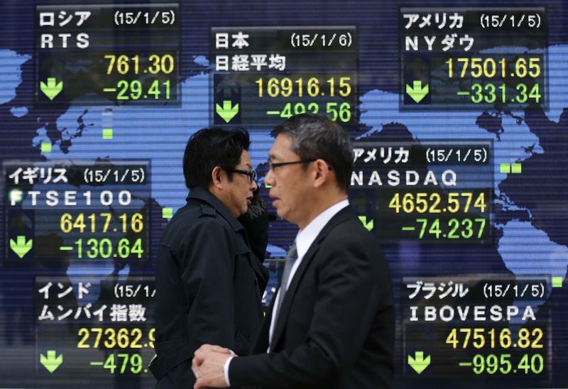 © Reuters. Passersby walk past in front of an electronic board displaying Japan's Nikkei average and various countries' stock price index outside a brokerage in Tokyo