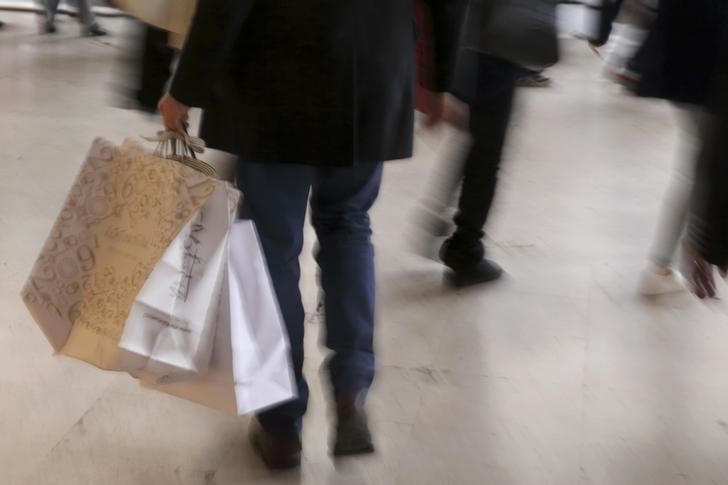 © Reuters. A man carries bags with purchases as shoppers take care of their last-minute Christmas holiday gift needs in Paris