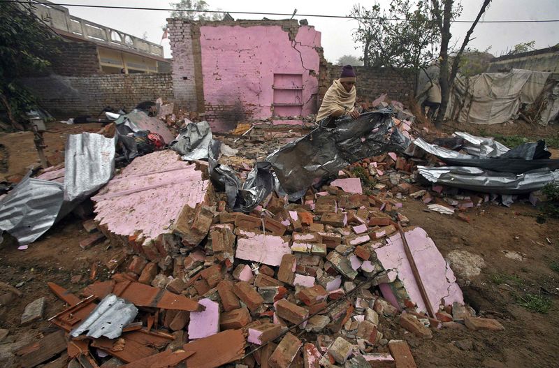 © Reuters. An Indian villager clears the debris from his house at Bainglad village