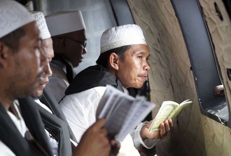 © Reuters. Clérigo muçulmano durante oração por vítimas do voo QZ 8501 da AirAsia, dentro de helicóptero da Força Aérea da Indonésia sobre o Mar de Java