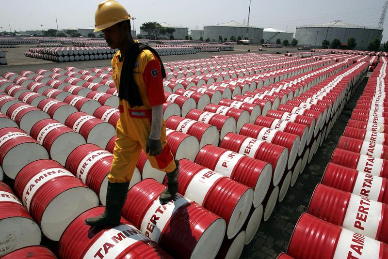 © Reuters. File photo of an employee of Indonesian oil company Pertamina walking on the top of drums at Jakarta's oil storage depot.