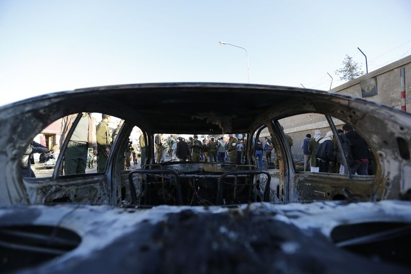 © Reuters. Policemen gather at the scene of a car bomb outside the police college in Sanaa