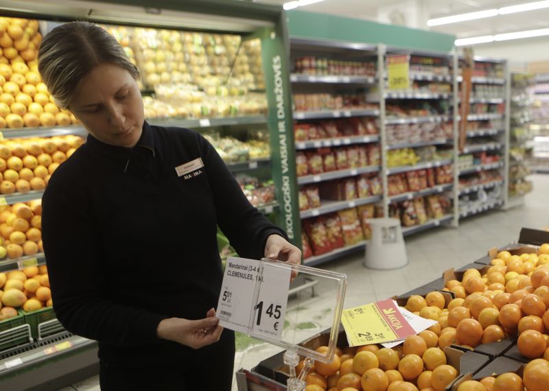 © Reuters. A worker changes price tags before a shop opens in Vilnius