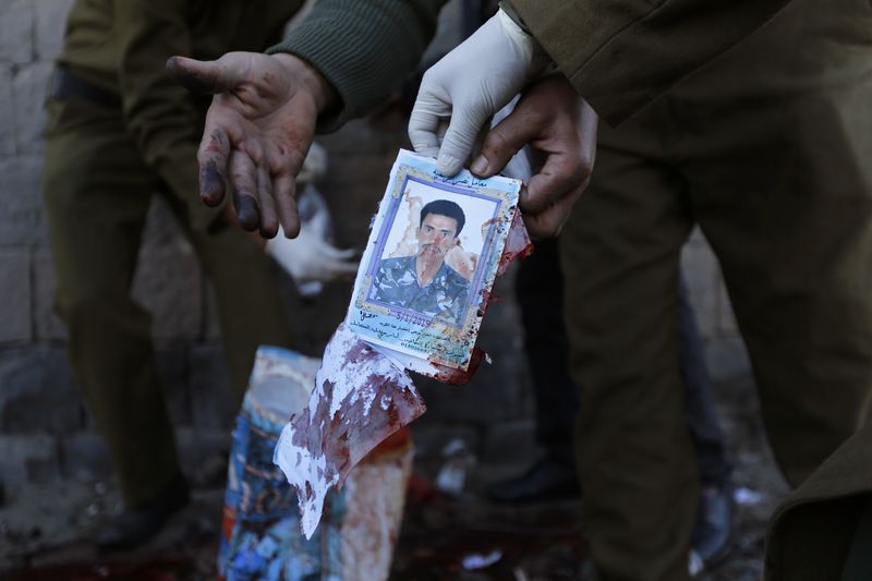 © Reuters. Policial segura foto de vítima de explosão de carro-bomba do lado de fora de academia policial em Sanaa