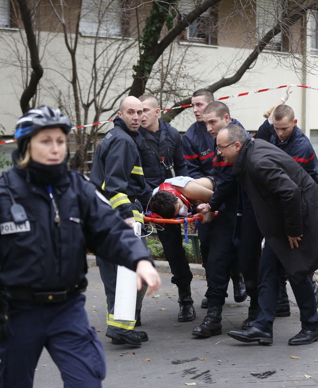 © Reuters. Bombeiros levam vítima em maca após ataque a jornal satírico em Paris