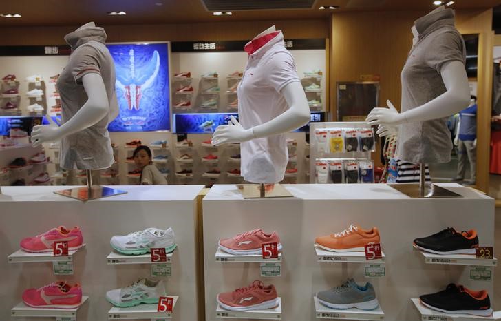 © Reuters. A woman is seen behind shelves displaying Li Ning shoes and shirts at a store in Beijing