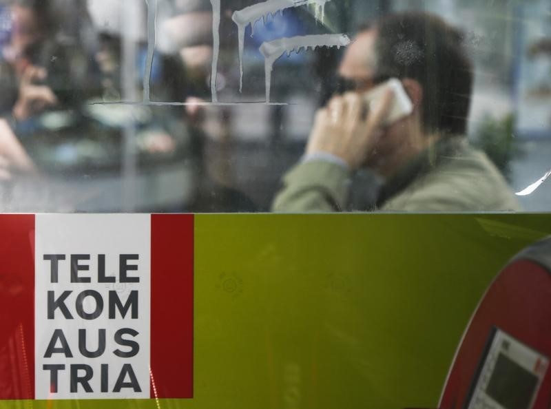 © Reuters. A man makes a phone call behind a sign of Telekom Austria in Vienna