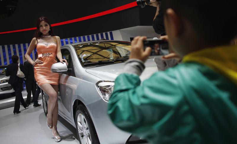 © Reuters. File photo of a child taking a picture of a model as she poses next to a car during the the 15th Shanghai International Automobile Industry Exhibition in Shanghai