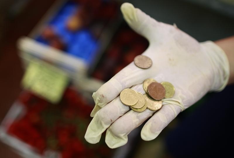 © Reuters. A fruit seller holds euro coins in a market in downtown Rome