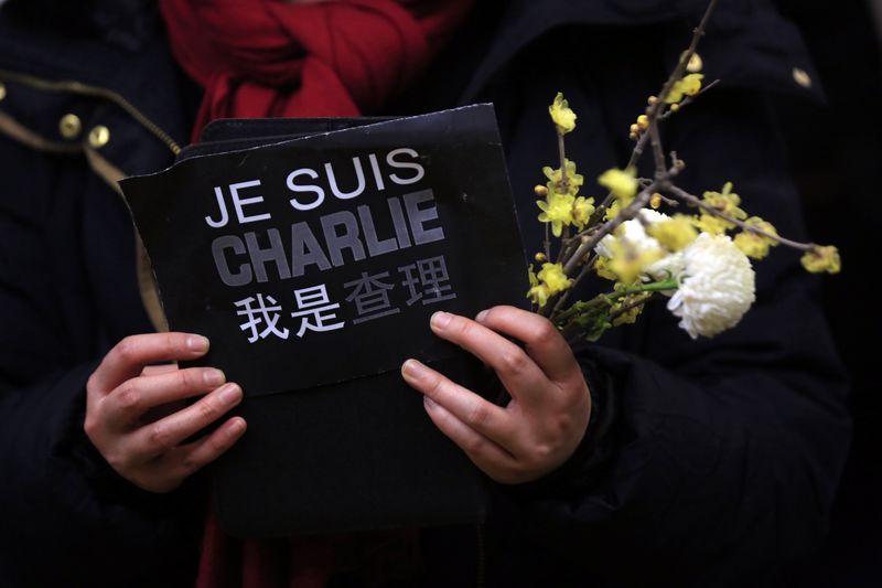 © Reuters. Mulher segura cartaz em homenagem a vítimas de ataque a jornal Charlie Hebdo em Paris