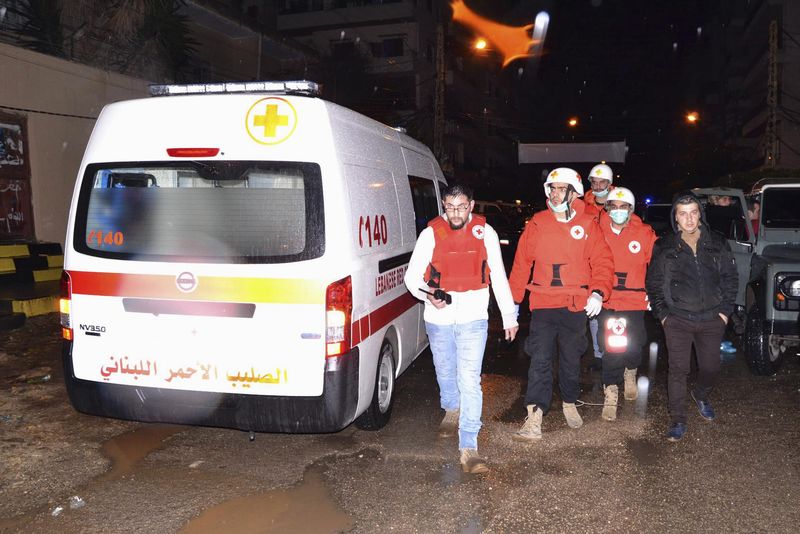 © Reuters. Lebanese Red Cross members walk in an area beside a cafe where a suicide bomb attack took place in Jabal Mohsen, Tripoli